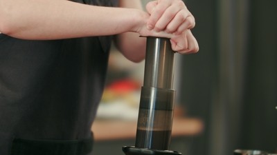 man pressing down on aeropress with both hands