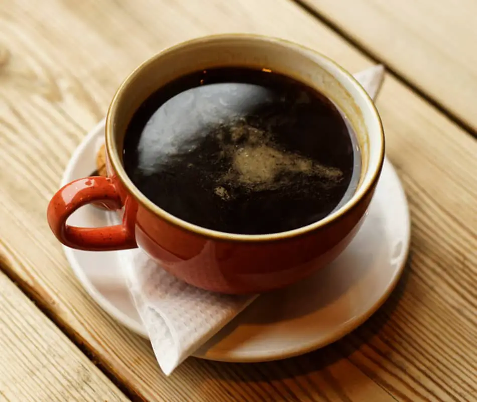 cup of americano coffee sitting on folded serviette and saucer