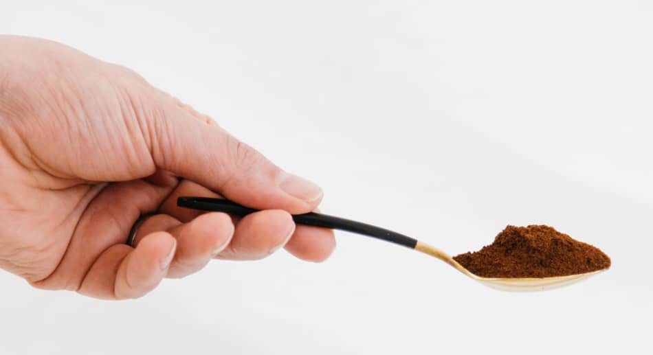 hand holding a heaped spoon of ground coffee