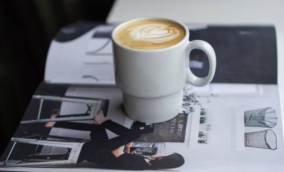 cup of cortado coffee sitting on top of a magazine