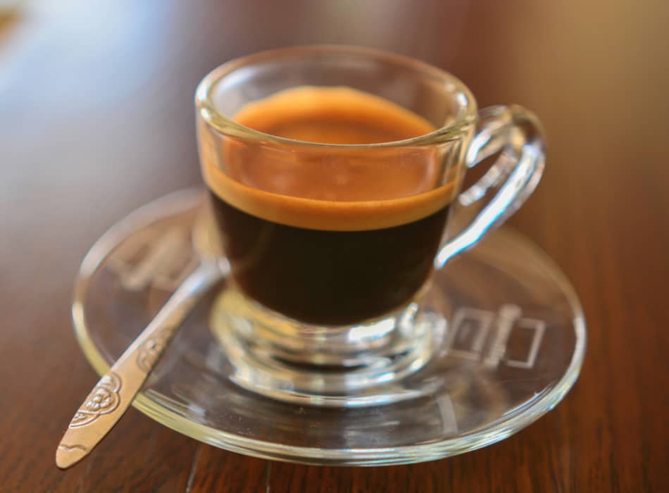 a cup of fresh espresso on saucer with teaspoon