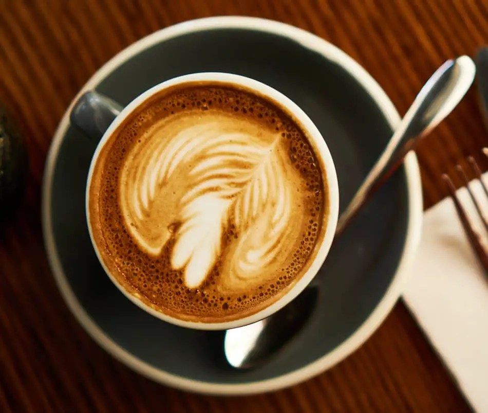 cup of flat white coffee in grey cup and saucer with spoon