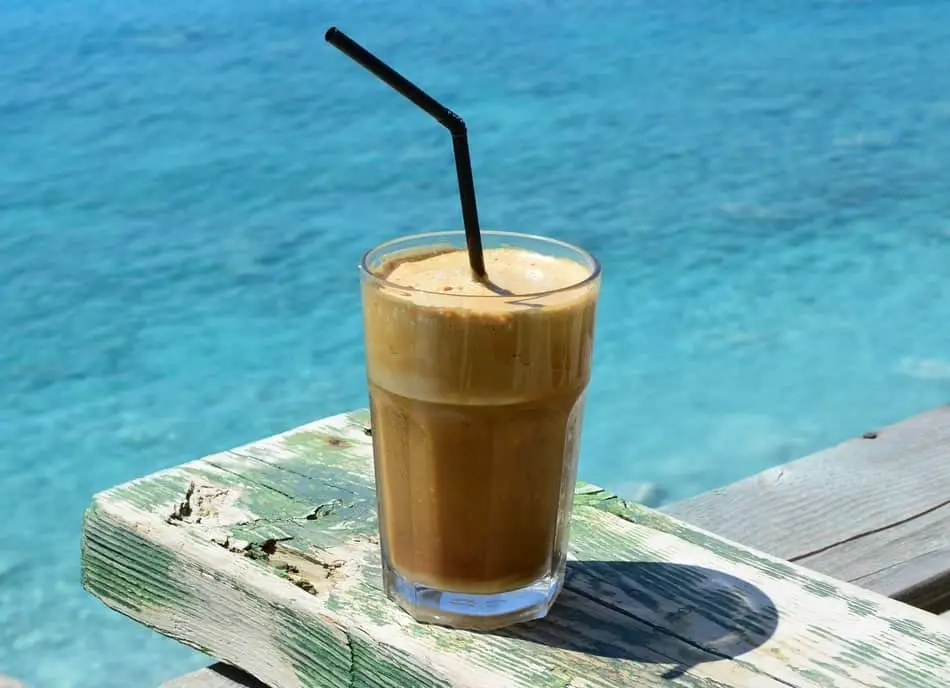 glass of ice cold greek frappe coffee overlooking blue sea