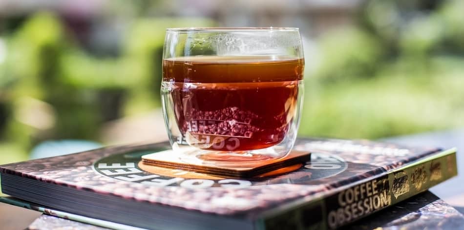 glass of coffee sitting on top of coffee obsession book