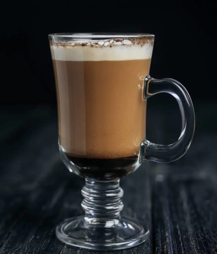 a glass cup of fresh irish coffee dusted with cocoa powder