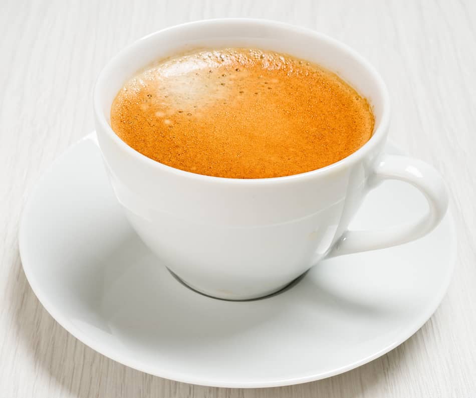 a fresh cup of lungo coffee in white cup and saucer