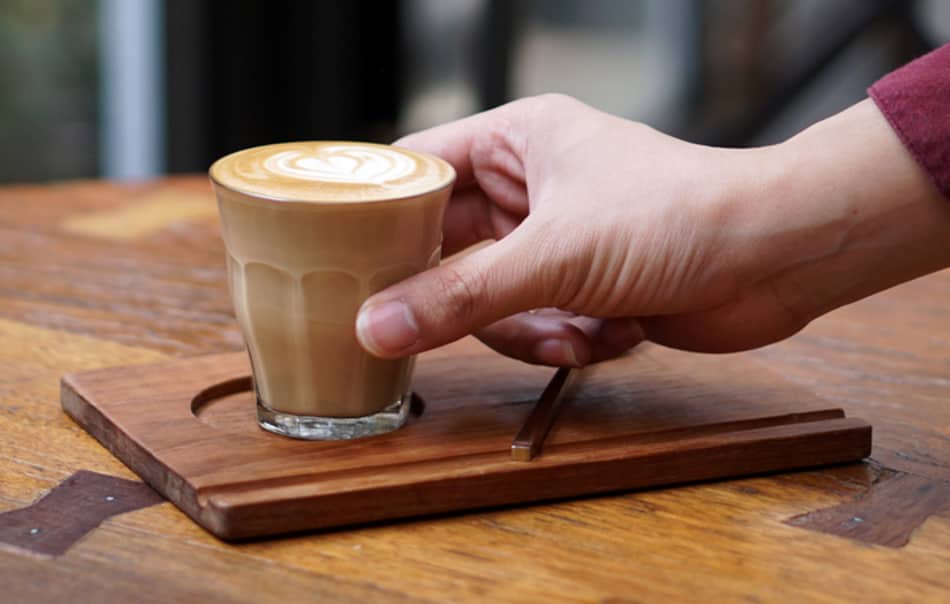 hand about to pick up a glass of piccolo coffee