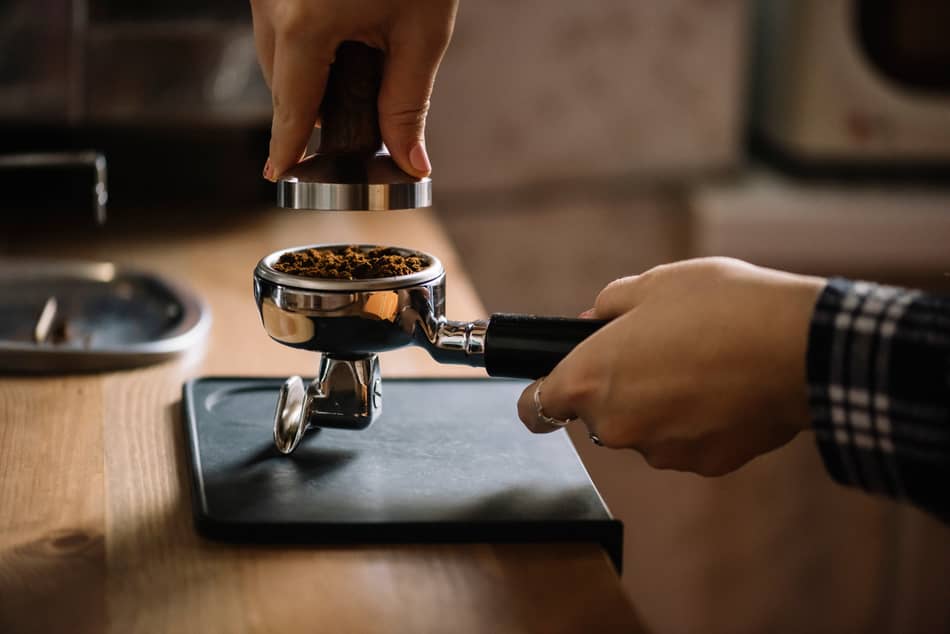 person about to tamp espresso inside the portafilter