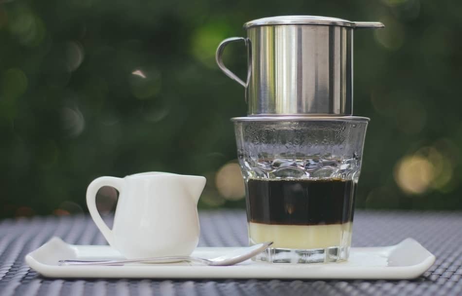 vietnamese coffee brewing over glass with condensed milk