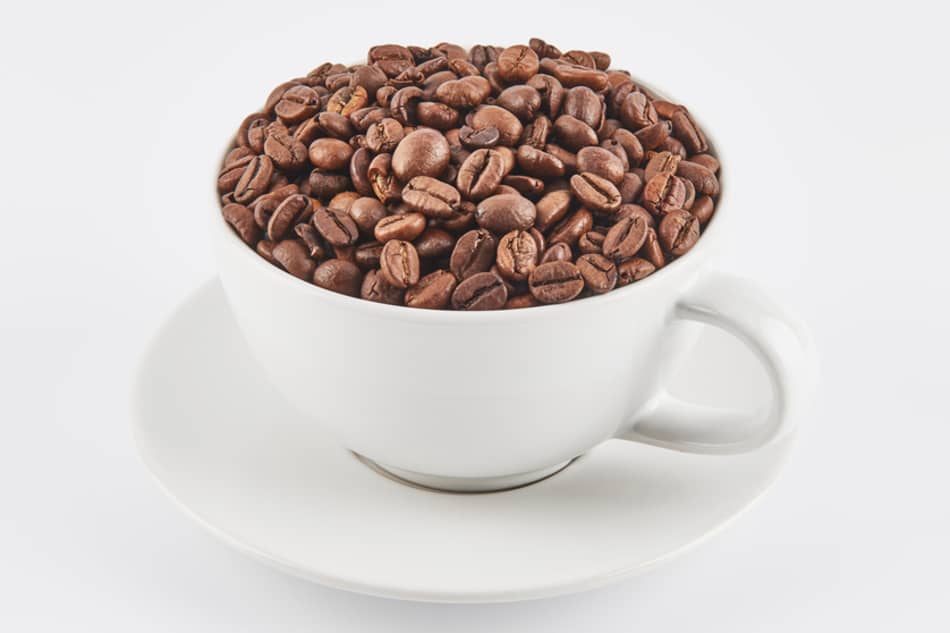 a white cup that is full of whole coffee beans