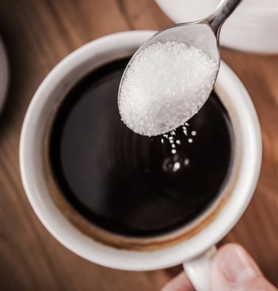 A teaspoon adding sugar to black coffee