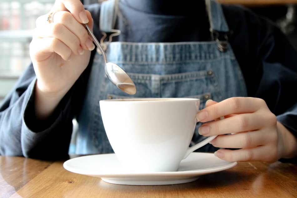 person about to stir their coffee